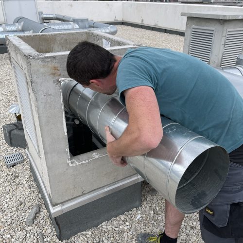 o2lclim-artisan-climatisation-val-de-marne-94-03 Techniciens spécialisés en installation de climatisation travaillant méticuleusement à la pose de conduits aériens en métal sur le toit.