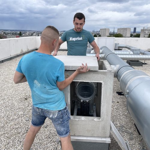 o2lclim-artisan-climatisation-val-de-marne-94-04 Deux techniciens en climatisation collaborant pour installer une unité extérieure de climatiseur, sous un ciel clair.